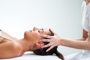 Close up of chiropractor doing healing osteopathic treatment on woman.Hands on head.